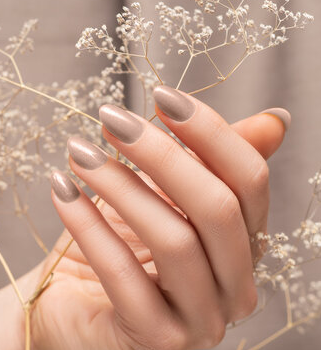 Nahaufnahme von Händen mit zartem Nude-Beige-Lack und Schleierkraut